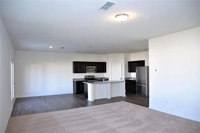 a living room with stainless steel appliances kitchen island a flat screen tv and a refrigerator