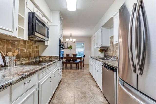 a kitchen with stainless steel appliances granite countertop a refrigerator a stove and a sink