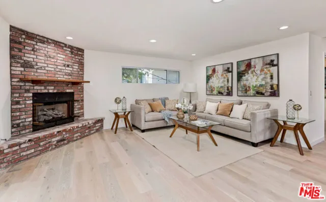 a living room with furniture potted plant a fireplace and a large window