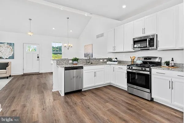 a kitchen with stainless steel appliances white cabinets a sink a stove a refrigerator and white cabinets