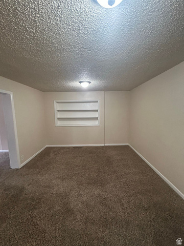 265 Rigdon Avenue, Unit 1 Salt Lake City, UT 84115 - Photo 6 of 15 Carpeted room featuring a built-in shelving unit, neutral wall paint, and white trim
