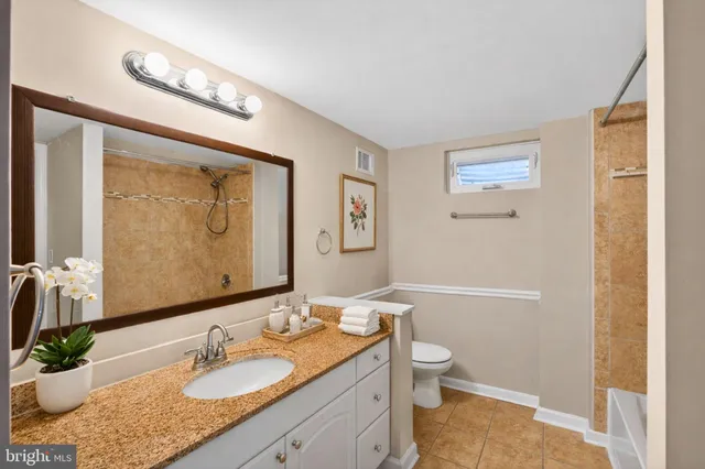 a bathroom with a granite countertop sink toilet and shower