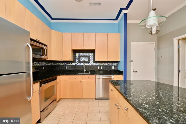 a kitchen with stainless steel appliances granite countertop a sink and a refrigerator