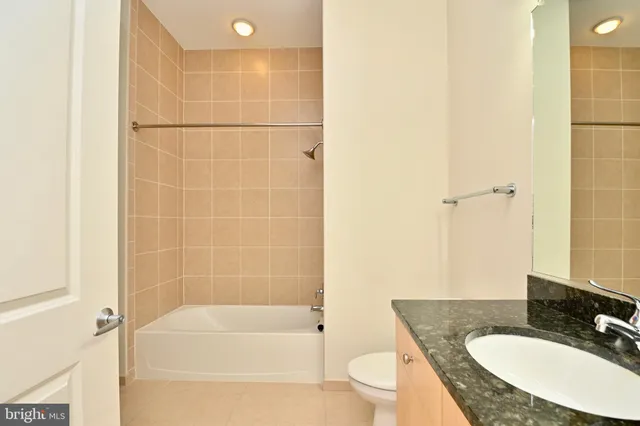 a bathroom with a granite countertop sink a toilet a mirror and shower