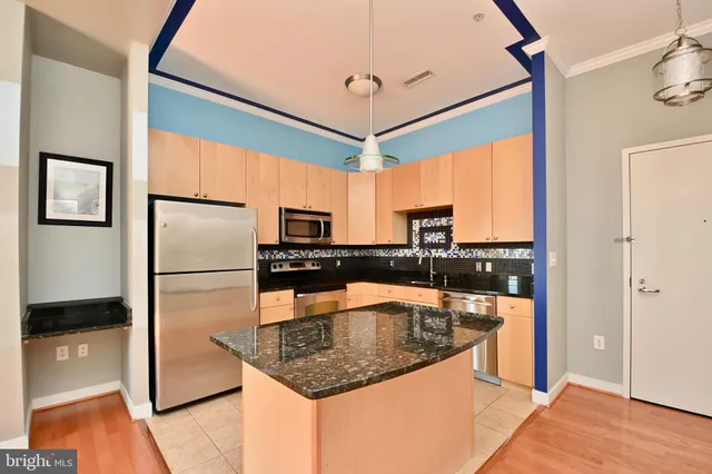 a kitchen with stainless steel appliances granite countertop a refrigerator a stove and a sink with wooden floor