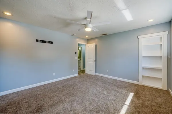 an empty room with closet and a ceiling fan