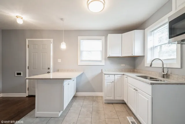 a kitchen with a sink dishwasher a stove and white cabinets