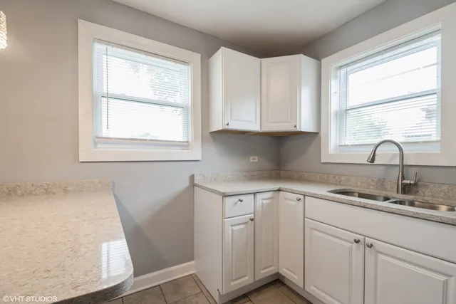 a kitchen with white cabinets window and sink