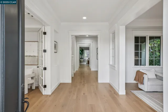 a view of a hallway with wooden floor and a bathroom