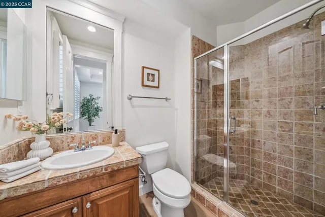 a bathroom with a granite countertop sink a toilet and shower
