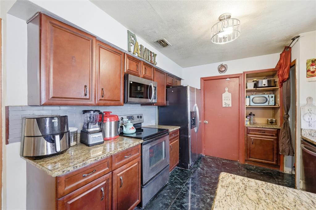 3027 Queens Gate Road Orlando, FL 32818 - Photo 17 of 34 a kitchen with stainless steel appliances granite countertop a refrigerator and a sink