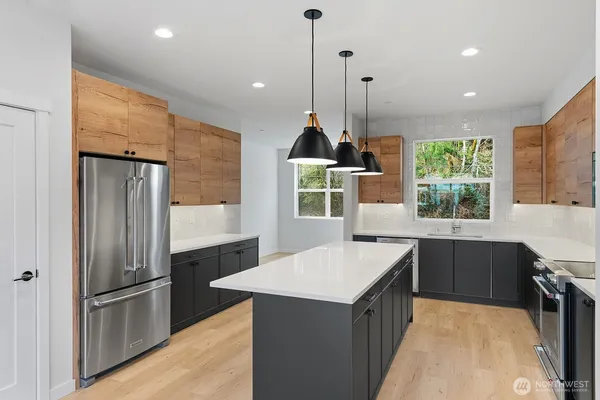 a kitchen with stainless steel appliances granite countertop a refrigerator a sink a stove and a wooden floors