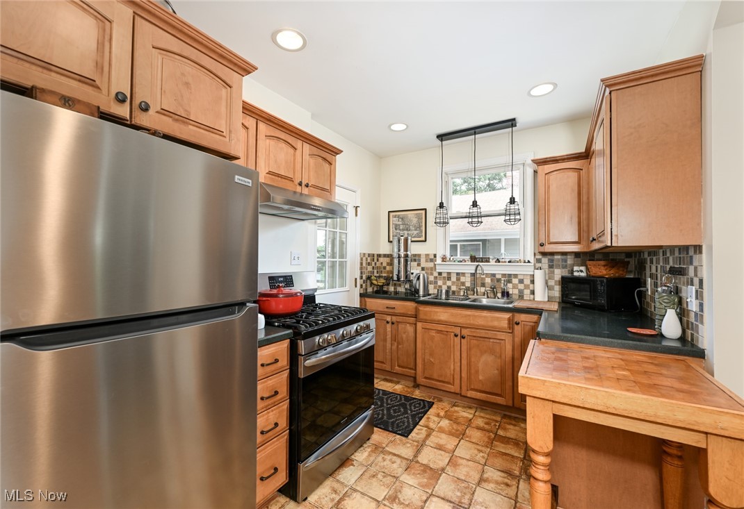 1236 Murray Avenue Akron, OH 44310 - Photo 10 of 29 Kitchen with stainless steel appliances, under cabinet range hood, tasteful backsplash, decorative light fixtures, and light stone finish flooring