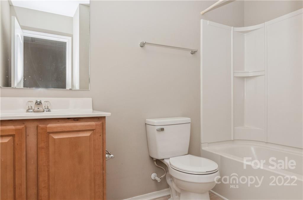 447 Hunters Dance Road, Unit 27 Fort Mill, SC 29708 - Photo 22 of 38 a bathroom with a granite countertop toilet a sink and a mirror