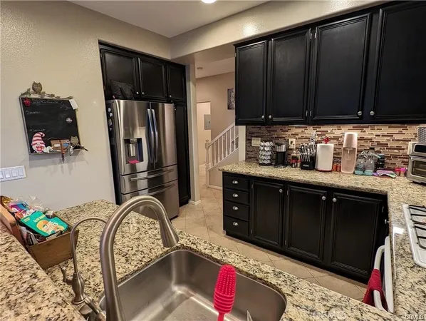 a kitchen with stainless steel appliances kitchen island granite countertop a refrigerator and a stove top oven