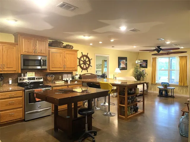 a kitchen with stainless steel appliances granite countertop a stove top oven a dining table and chairs with wooden floor