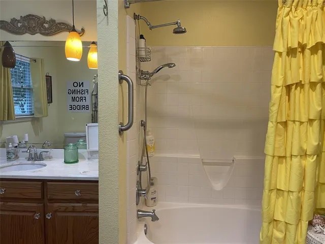 a bathroom with a granite countertop shower sink vanity and mirror