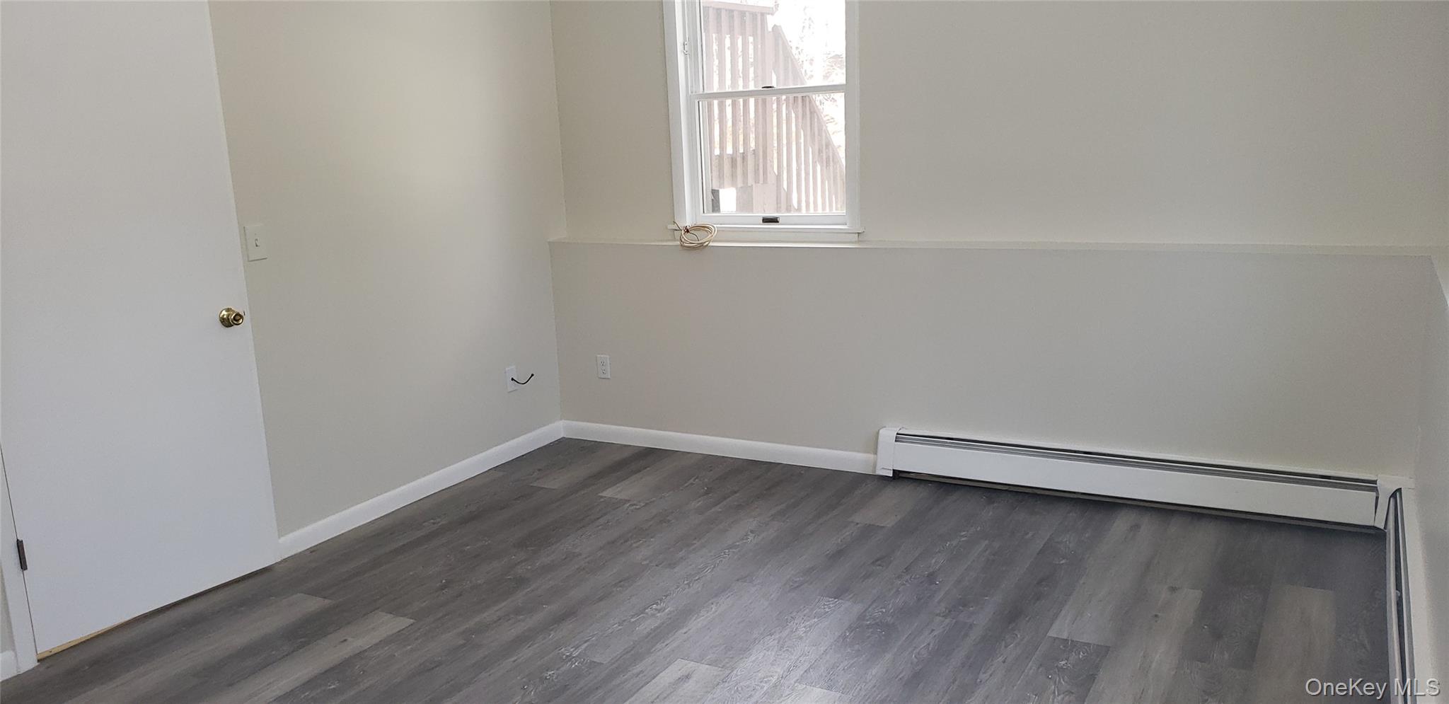 42 Upper Ferndale Road, Unit B Liberty, NY 12754 - Photo 12 of 18 Unfurnished room featuring a baseboard heating unit, dark wood-type flooring, and a baseboard radiator