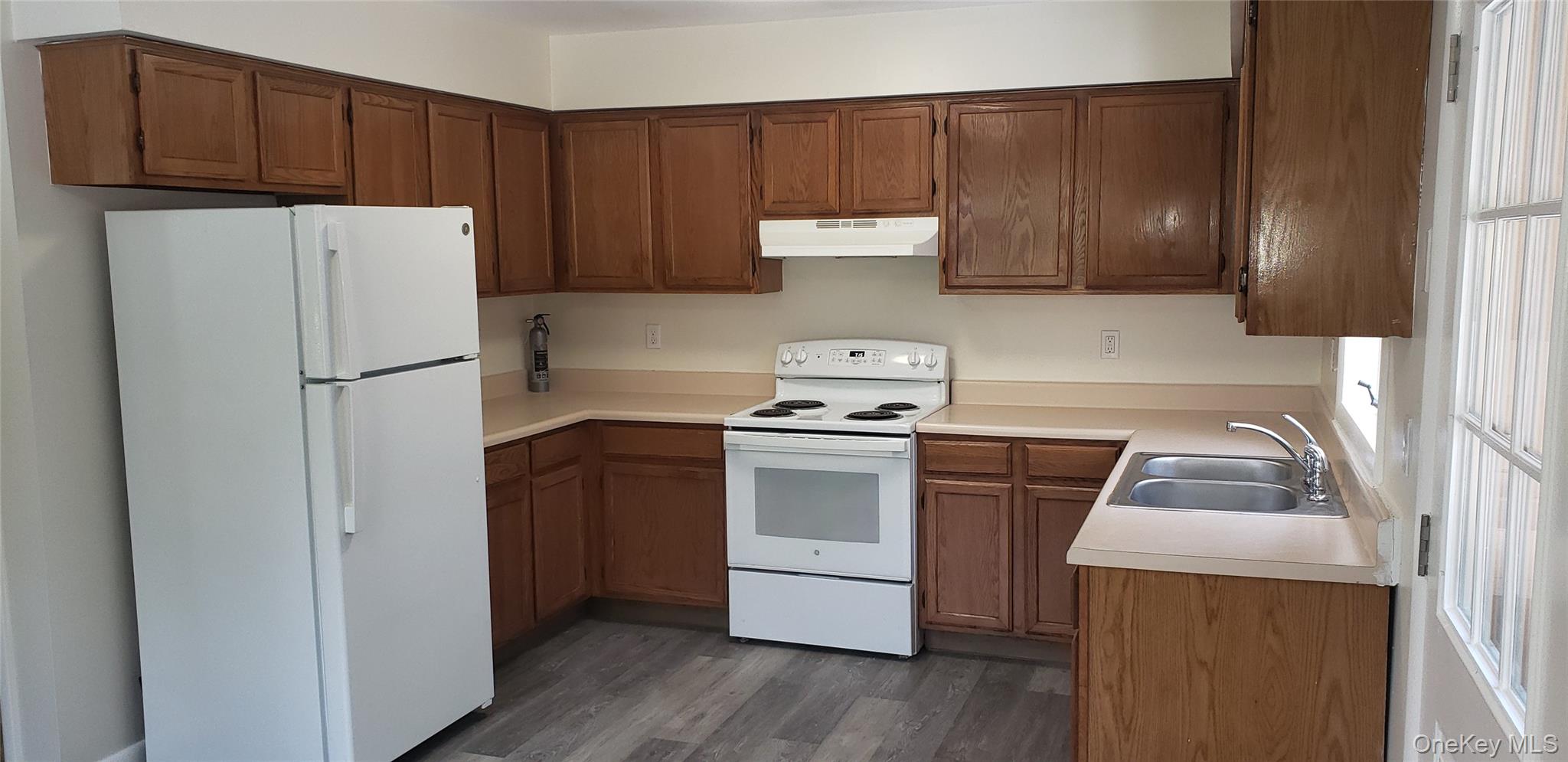 42 Upper Ferndale Road, Unit B Liberty, NY 12754 - Photo 2 of 18 Kitchen with white appliances, light countertops, brown cabinetry, dark wood-style floors, and under cabinet range hood