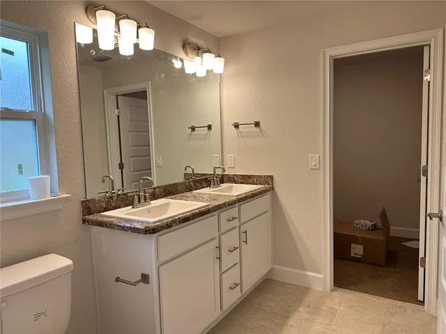 a bathroom with a granite countertop sink a toilet and a mirror