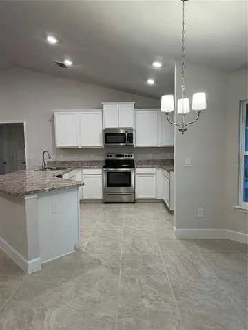 a kitchen with kitchen island granite countertop a stove top oven a sink a counter space and cabinets