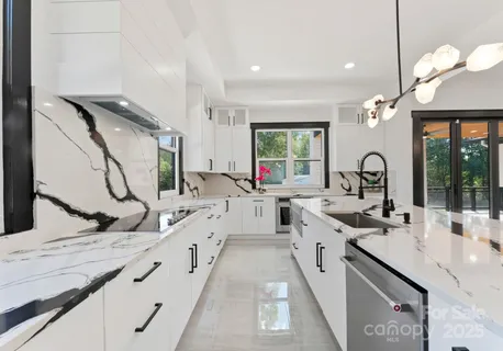 a large white kitchen with a granite countertop sink and a large window