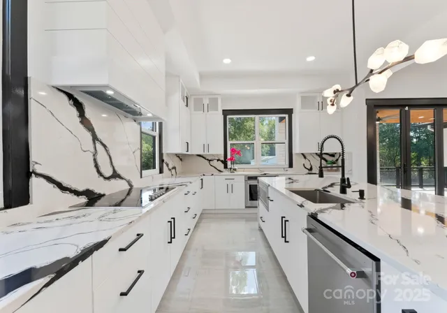 a large white kitchen with a granite countertop sink and a large window