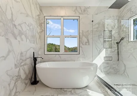 a white bath tub sitting in a bathroom next to a window