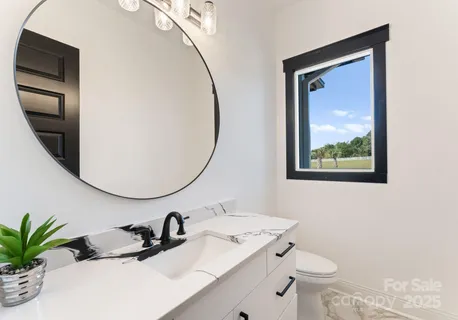 a bathroom with a granite countertop sink mirror vanity and toilet