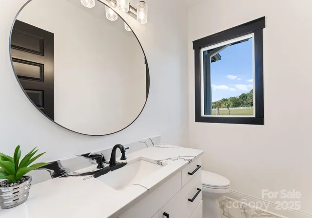 a bathroom with a granite countertop sink mirror vanity and toilet