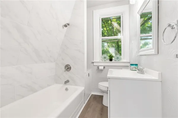 a bathroom with a sink a bathtub window and a toilet