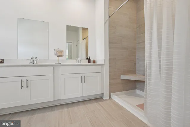a bathroom with a double vanity sink a toilet and shower