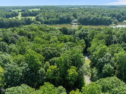 an aerial view of residential house with outdoor space and trees all around