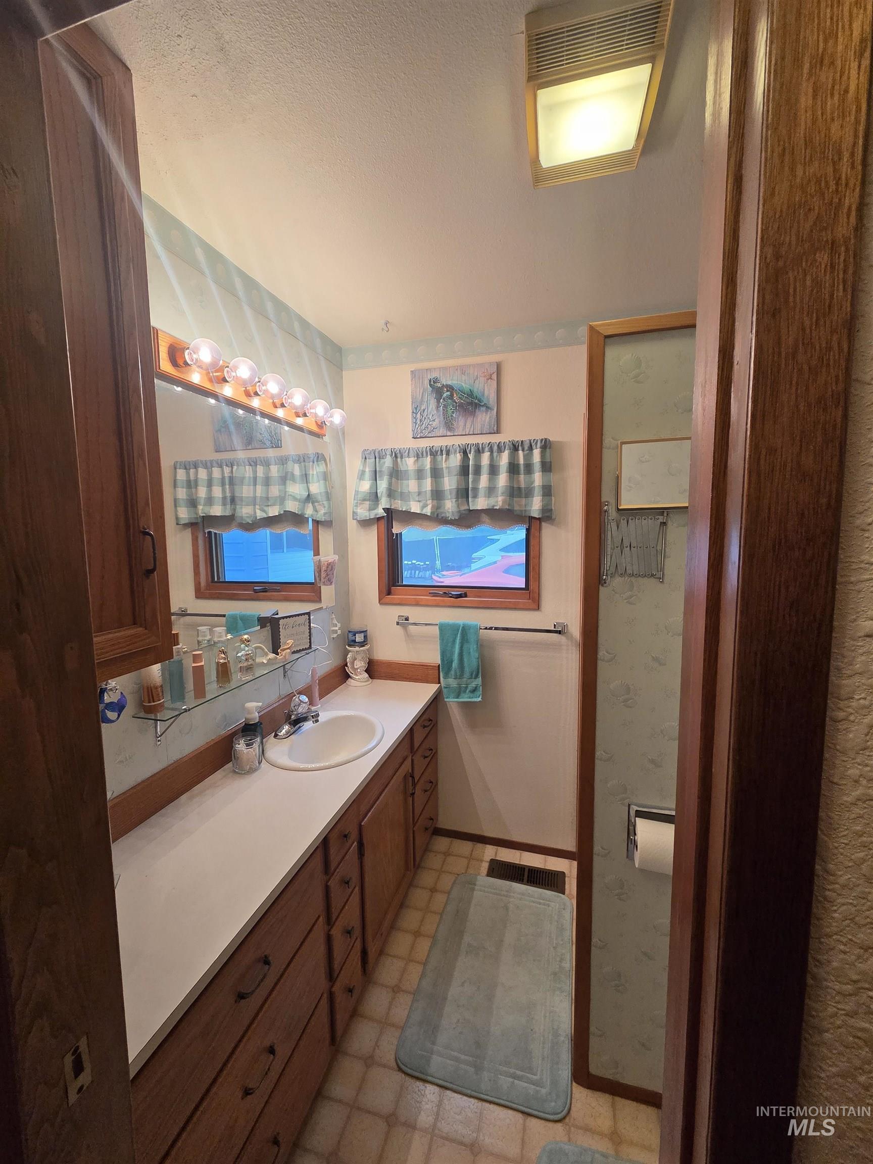 1607 Main Street Pomeroy, WA 99347 - Photo 18 of 28 Bathroom featuring vanity, light flooring, a textured ceiling, and wallpapered walls
