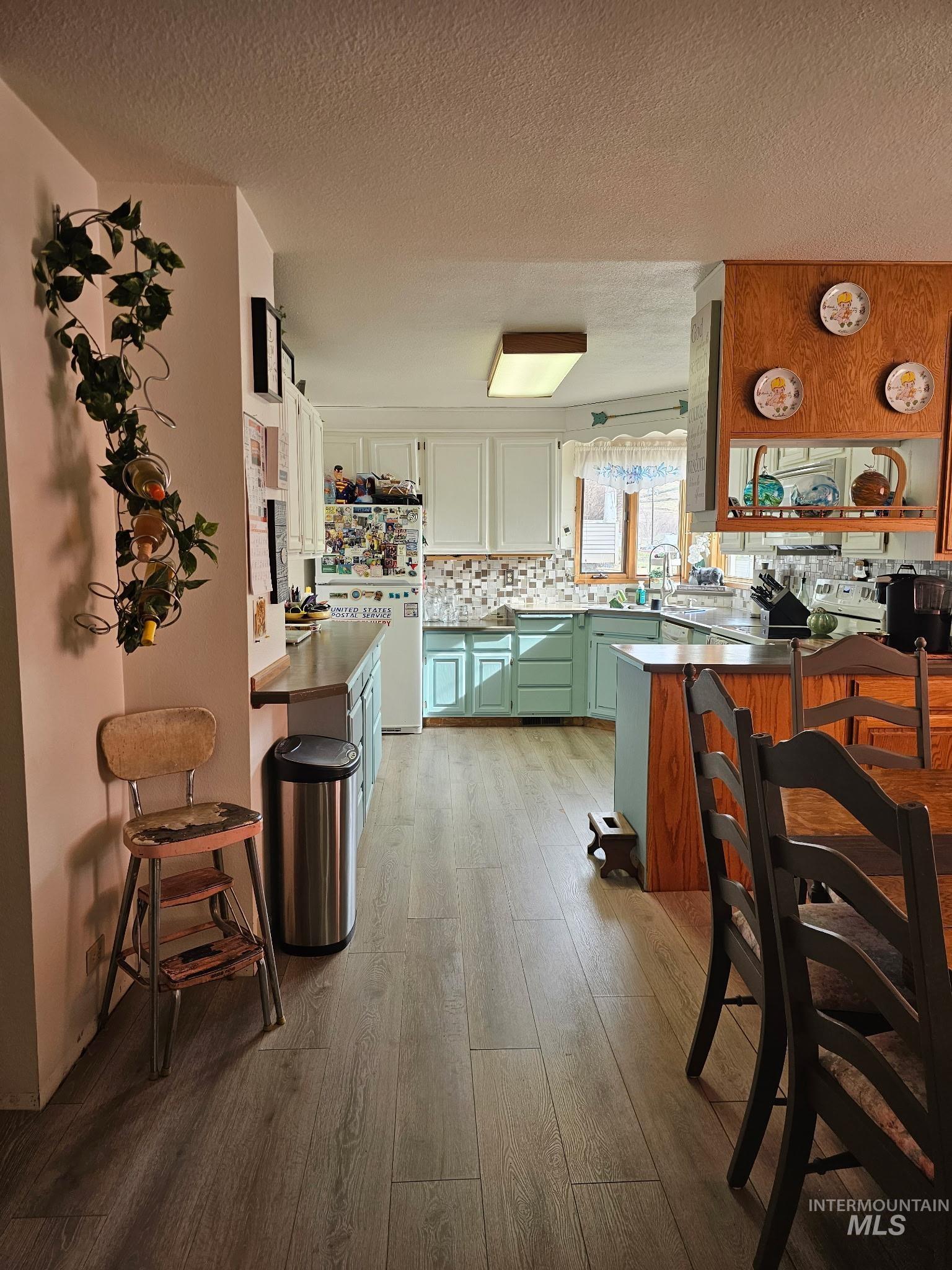 1607 Main Street Pomeroy, WA 99347 - Photo 6 of 28 Kitchen featuring a peninsula, a textured ceiling, freestanding refrigerator, two tone color scheme, and light wood-type flooring