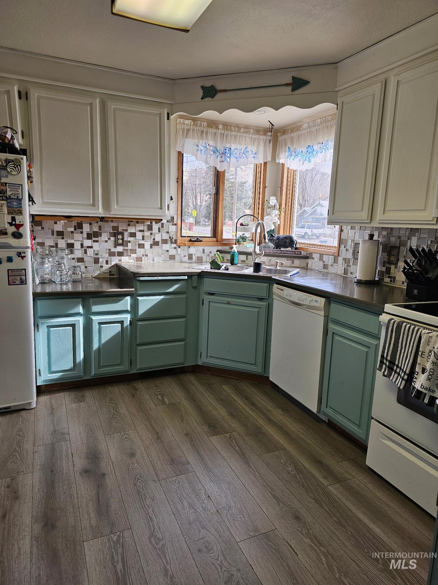 1607 Main Street Pomeroy, WA 99347 - Photo 7 of 28 Dual tone kitchen with white appliances, two tone color scheme, dark countertops, dark wood finished floors, and backsplash