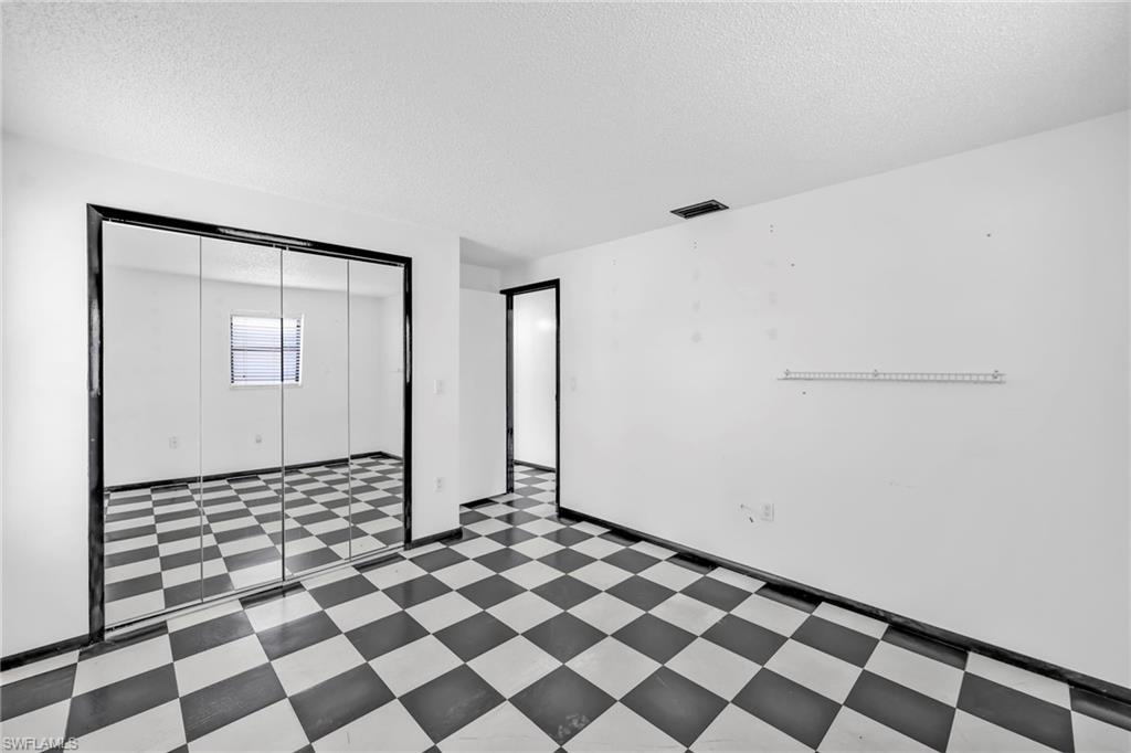 140 Blue Ridge Drive Naples, FL 34112 - Photo 18 of 26 Unfurnished bedroom with tile patterned floors, a textured ceiling, and a closet