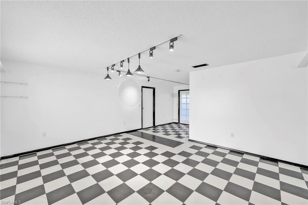 140 Blue Ridge Drive Naples, FL 34112 - Photo 3 of 26 Spare room featuring tile patterned floors, a textured ceiling, and track lighting