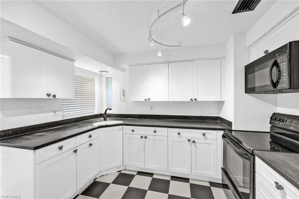 140 Blue Ridge Drive Naples, FL 34112 - Photo 9 of 26 Kitchen with black appliances, tile patterned floors, a sink, white cabinets, and a textured ceiling