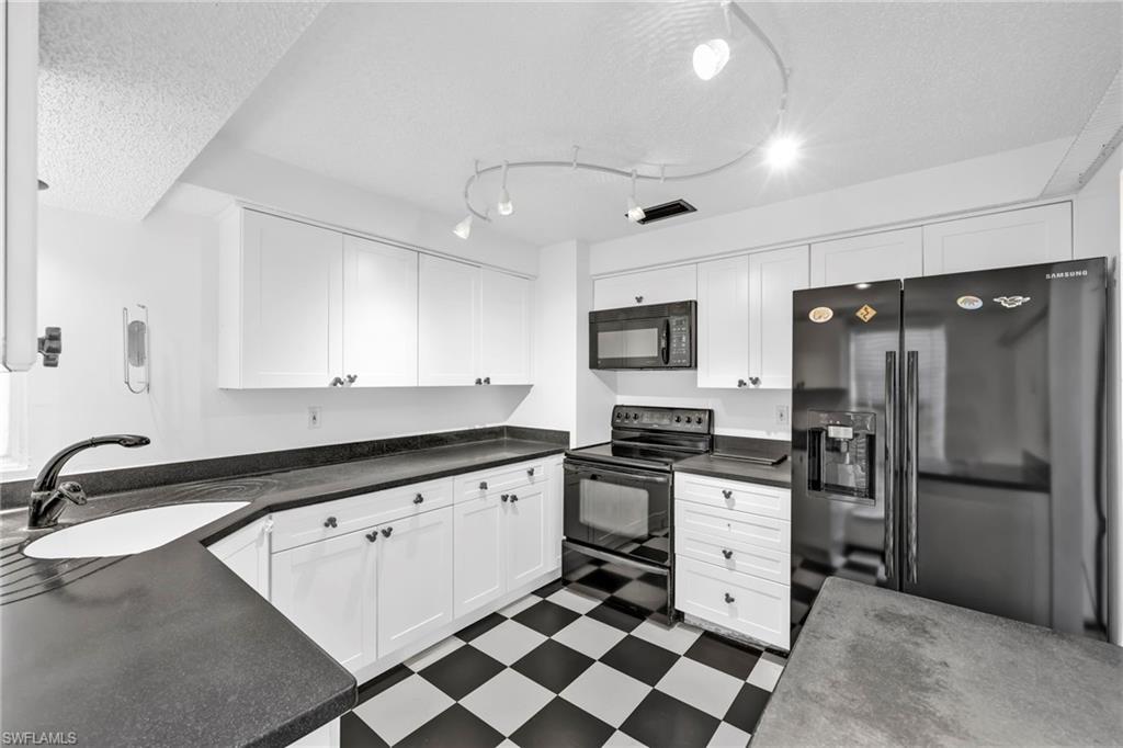 140 Blue Ridge Drive Naples, FL 34112 - Photo 10 of 26 Kitchen with black appliances, a sink, dark floors, a textured ceiling, and white cabinetry