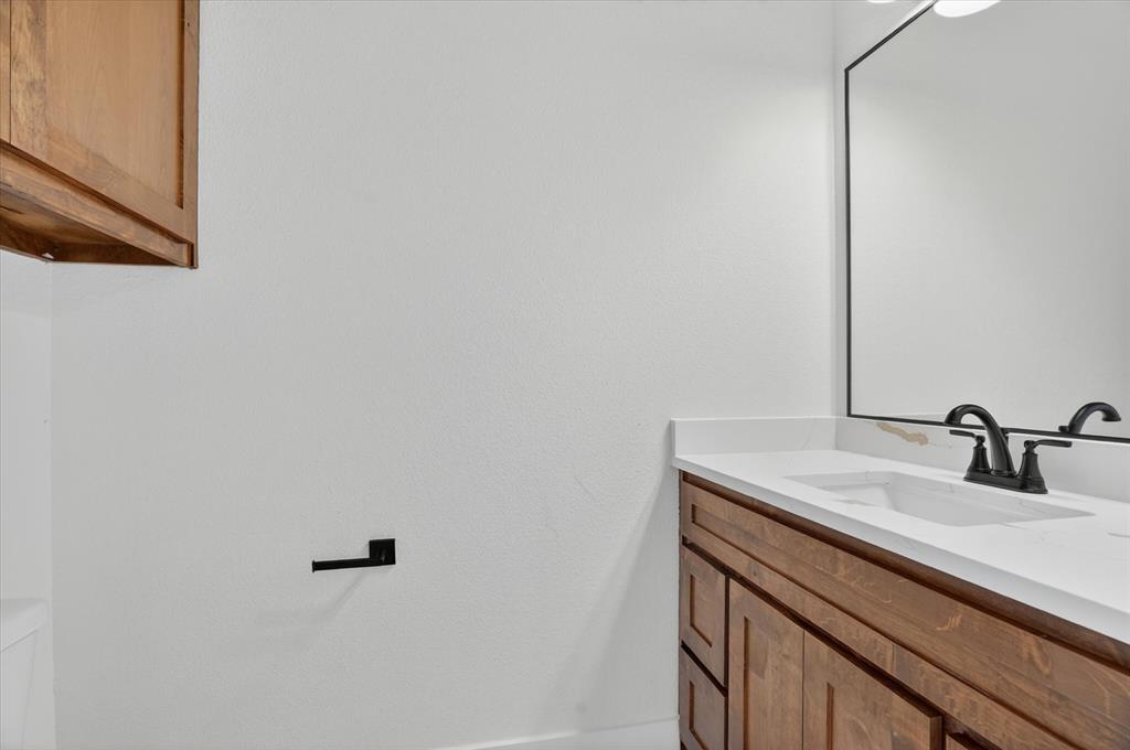 225 Kilkenny Road Poolville, TX 76487 - Photo 29 of 36 Bathroom vanity featuring a white countertop, under-mount sink, and dark bronze faucet