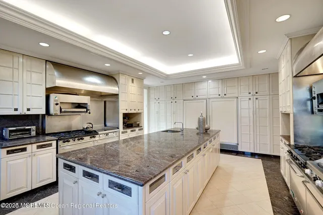 a large kitchen with a stove a sink a counter top space and cabinets