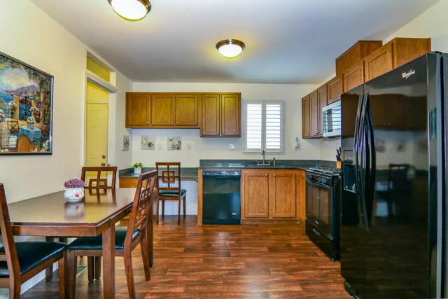 a kitchen with stainless steel appliances granite countertop a refrigerator a stove top oven a sink dishwasher and dining table with wooden floor