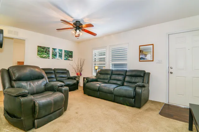 a living room with furniture a ceiling fan and a window