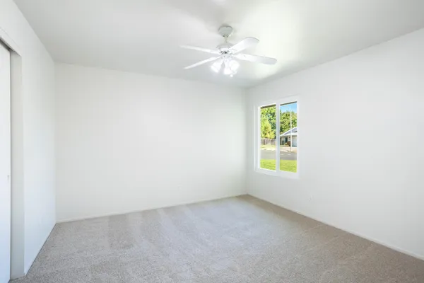 an empty room with windows and chandelier fan