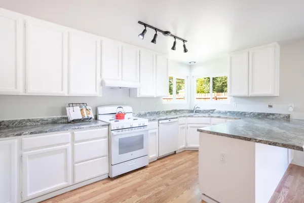 a kitchen with granite countertop a sink window and cabinets