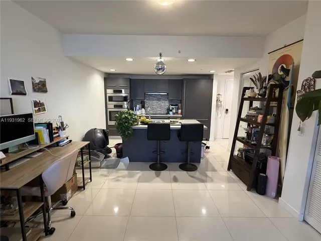 a living room with furniture a flat screen tv and a refrigerator