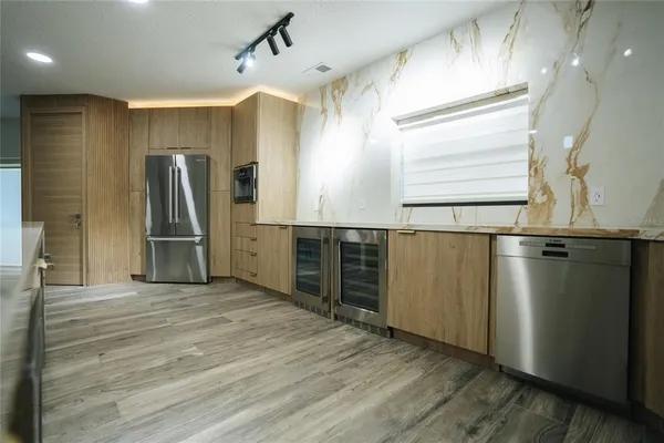 a large kitchen with stainless steel appliances a refrigerator and a sink