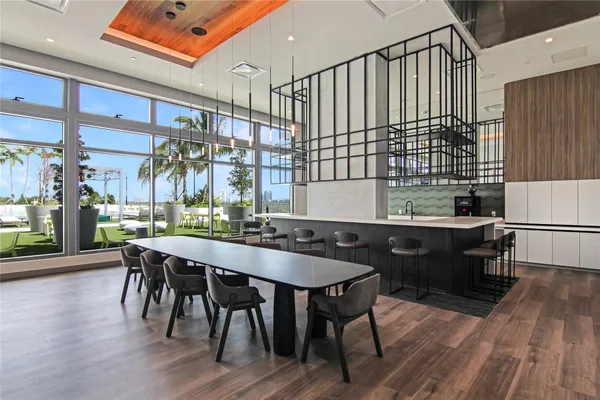 a dining hall with stainless steel appliances kitchen island granite countertop wooden floor a dining table and chairs