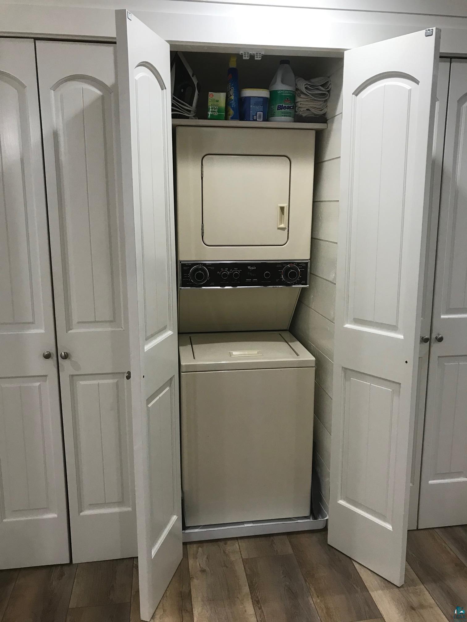 70745 Range Line Road Iron River, WI 54847 - Photo 31 of 40 Integrated laundry closet featuring a stacked washer and dryer, white paneled bifold doors, and wood-finish flooring